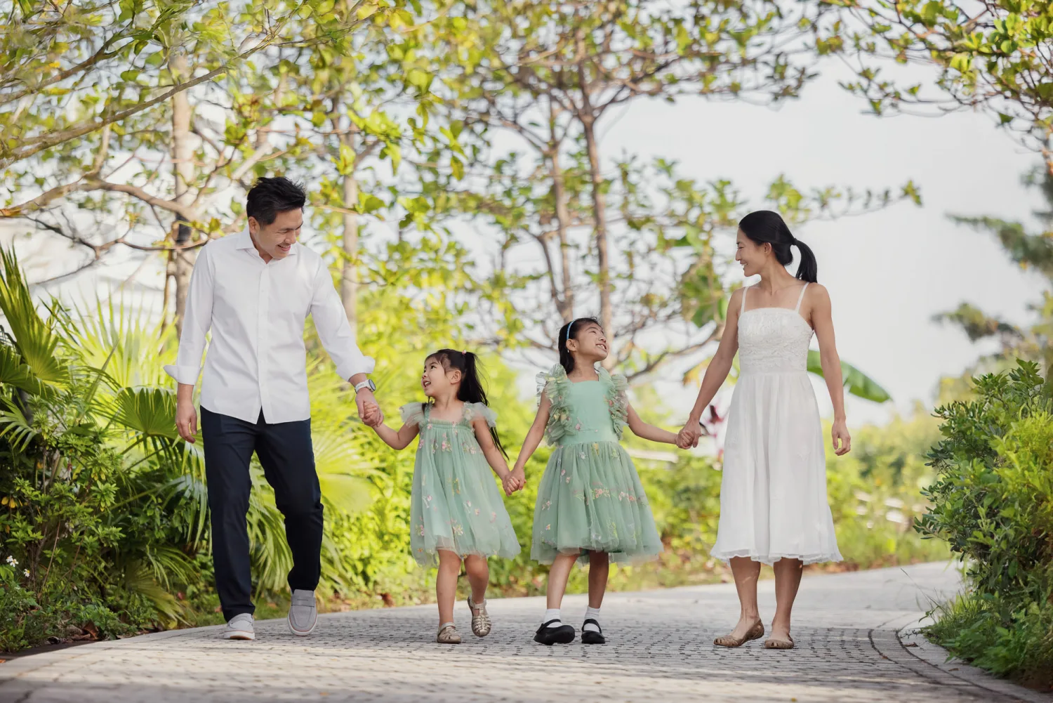 The family walking hand-in-hand along a tree-lined path in golden morning light