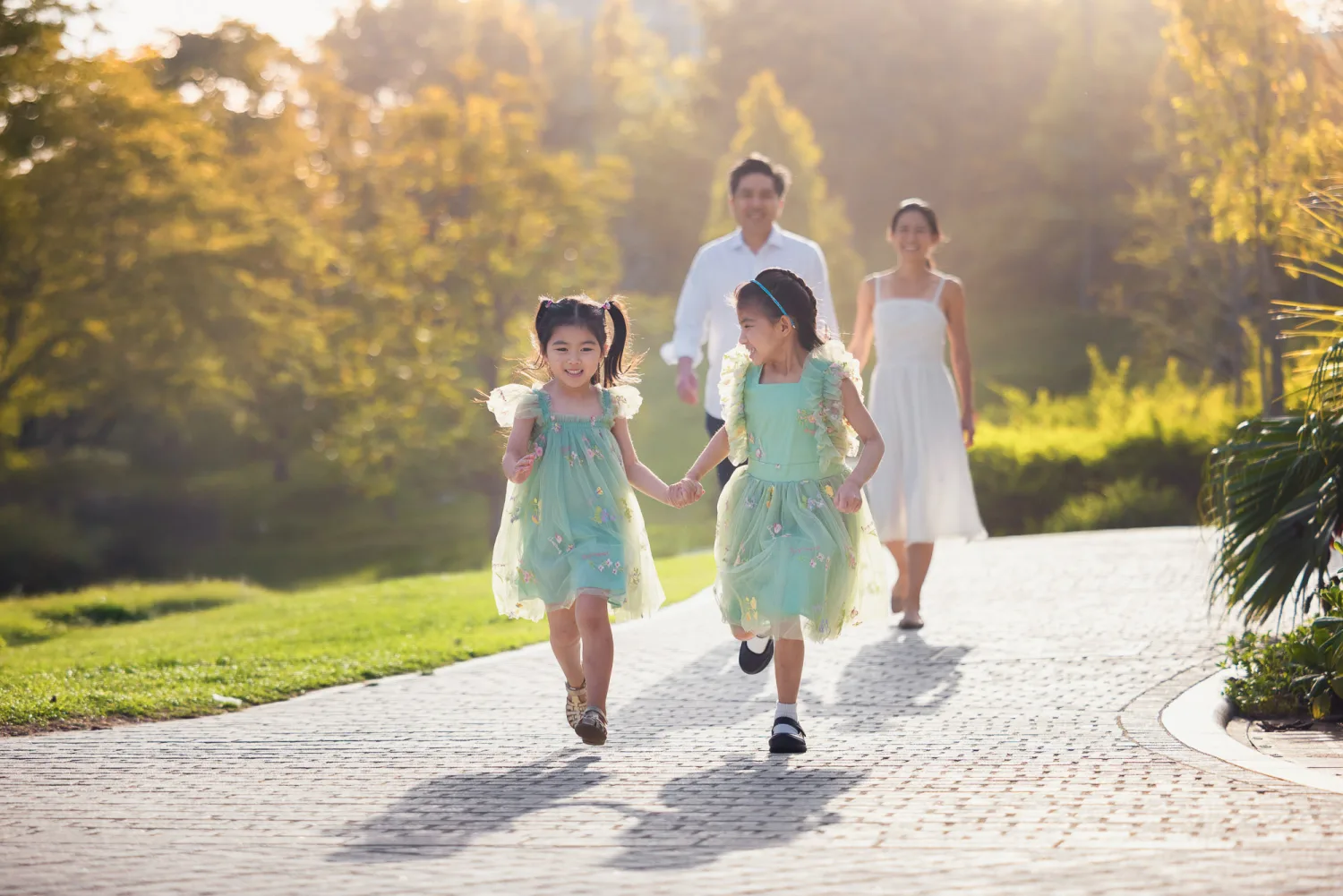 Sophie and Zoe running ahead in matching mint green dresses as their parents follow