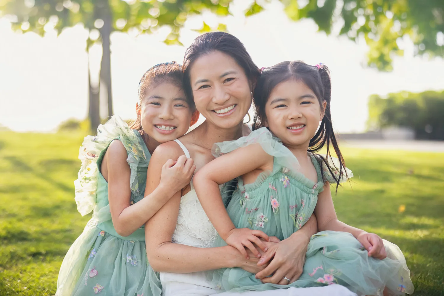 Suzanna sitting on the grass with Sophie and Zoe in warm golden sunrise light