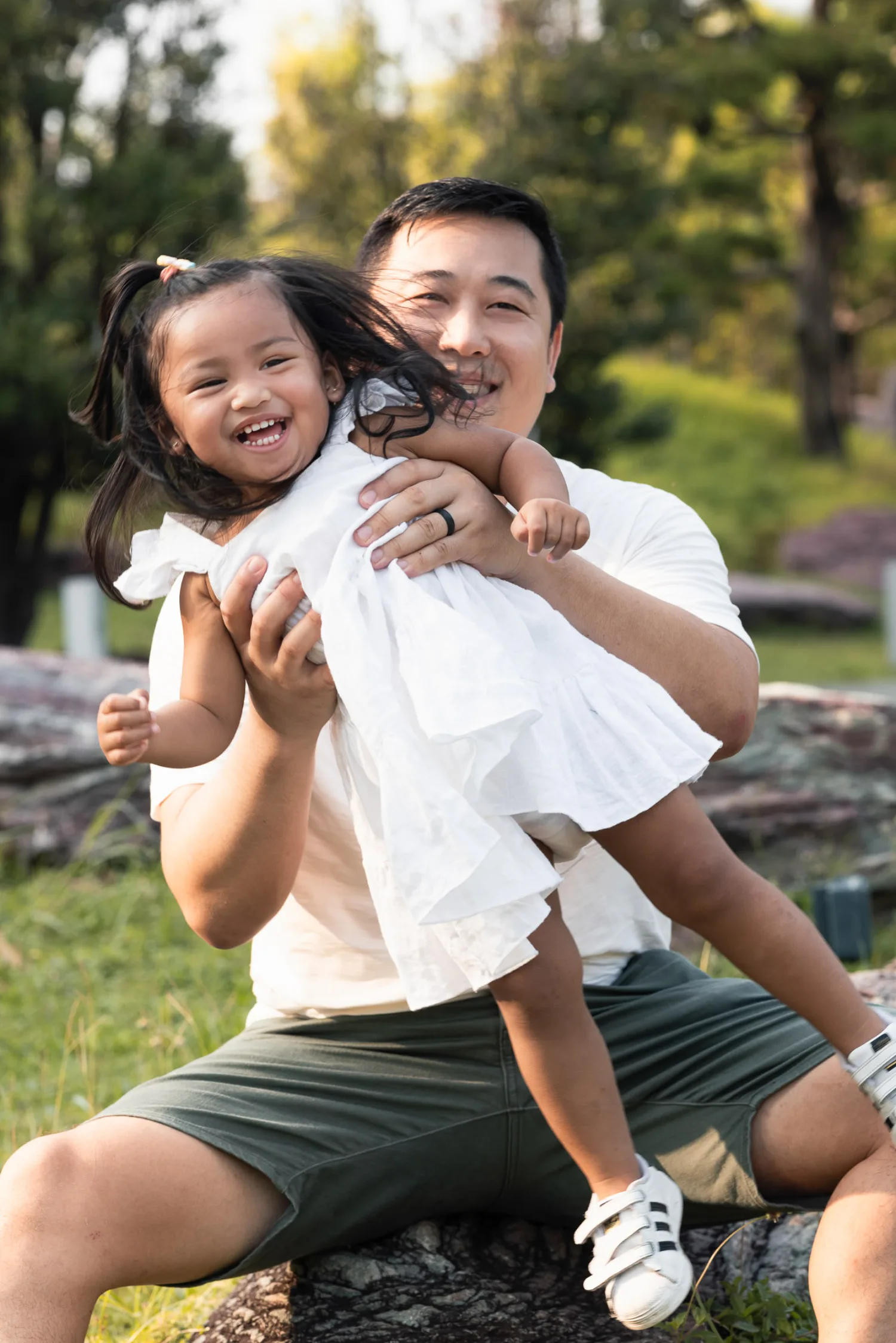 Dan and Gabby on a rock, both laughing, pigtails flying