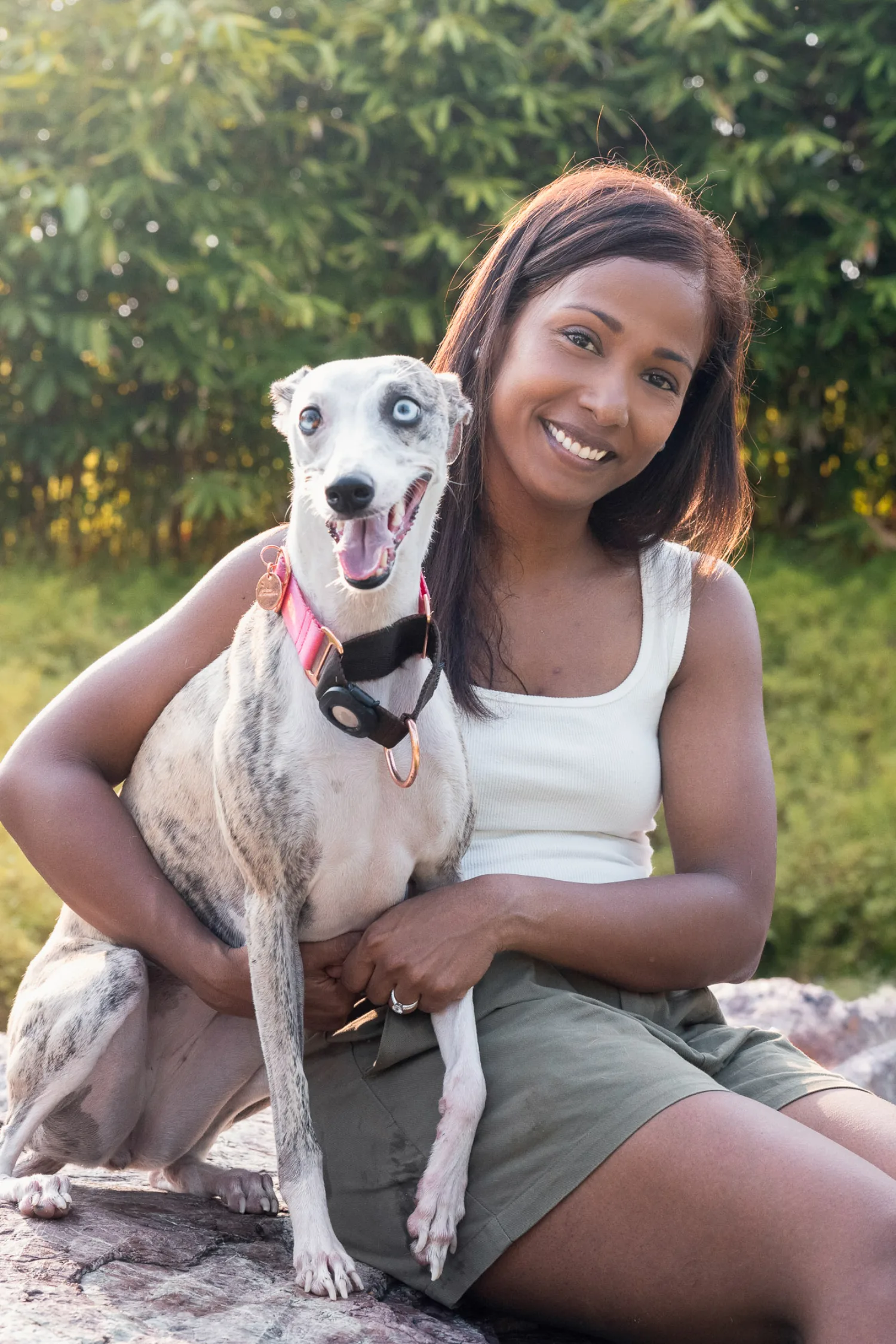 Jessica holding Luna close on a sunlit rock, both smiling