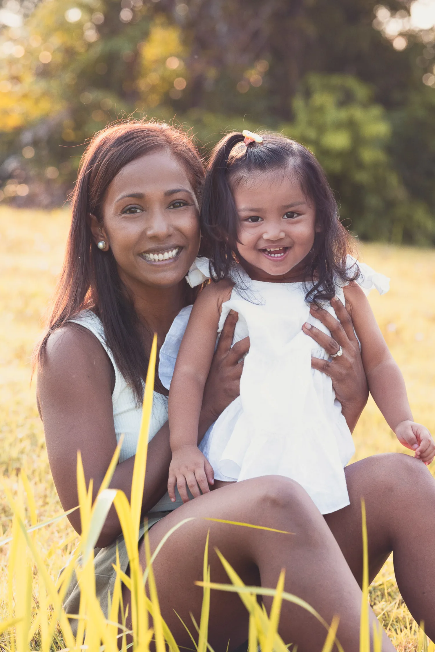 Jessica and Gabby sitting together in the tall grass, beaming